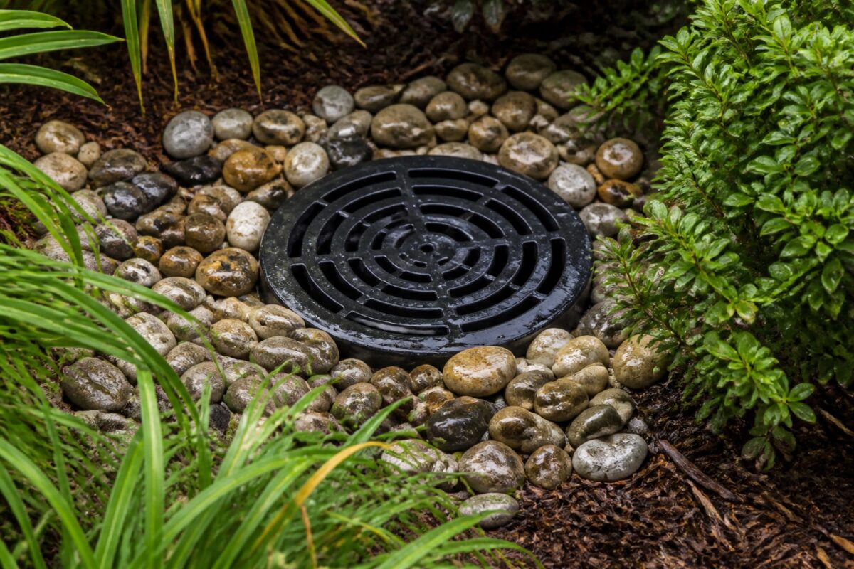 Round atrium drain grate set in river rock in a planting bed