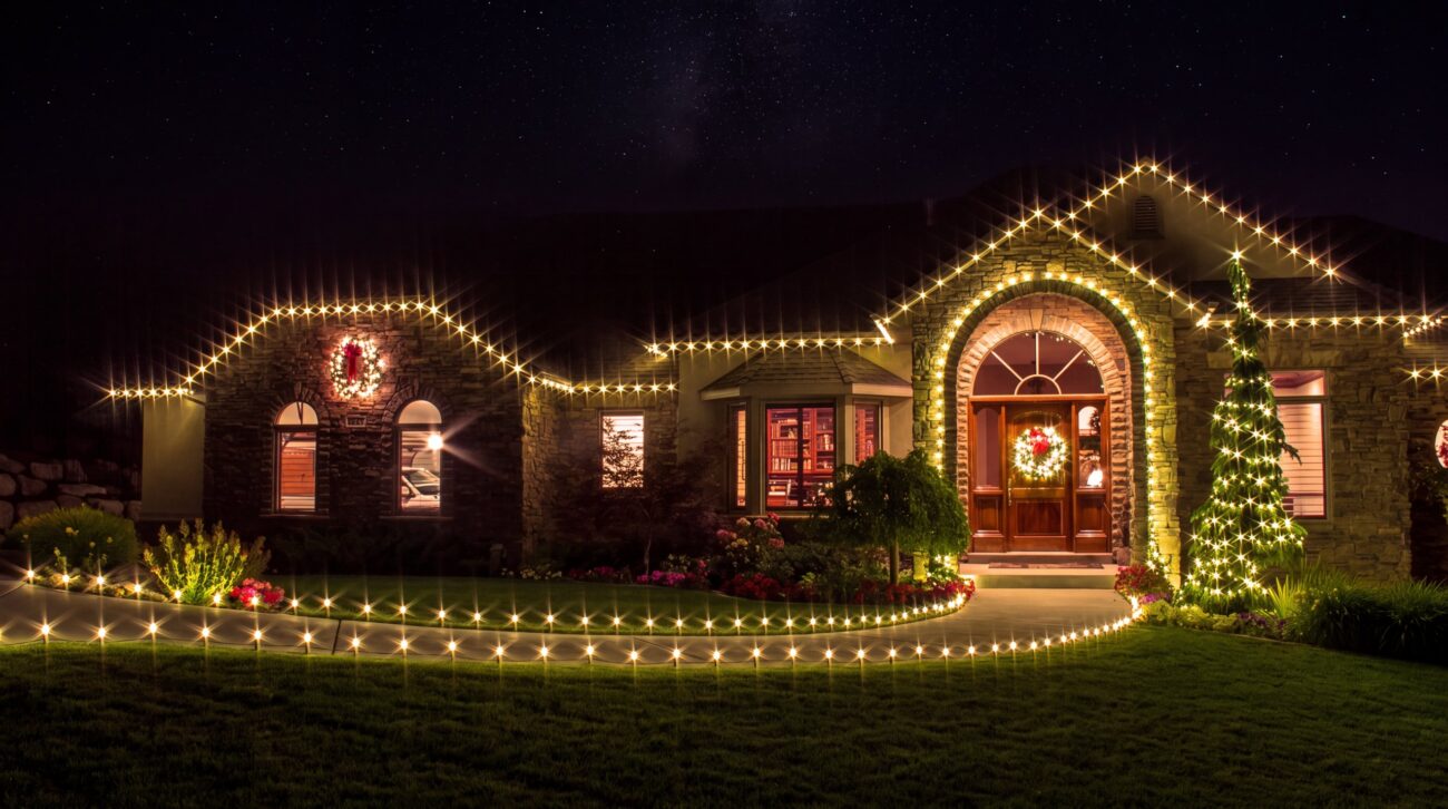 Warm white holiday lights along a roof edge, doorway, and front walk