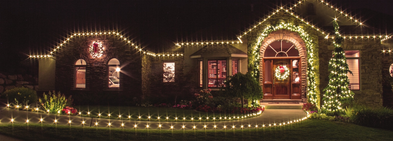 Warm white holiday lights along a roof edge, doorway, and front walk